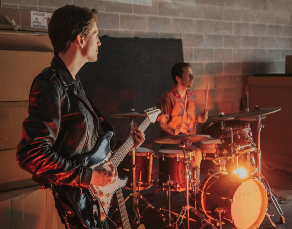 It can be hard to learn guitar. This is an image of a guitarist and drummer jamming together