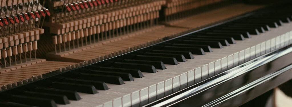 Upright piano keyboard with hammers exposed.