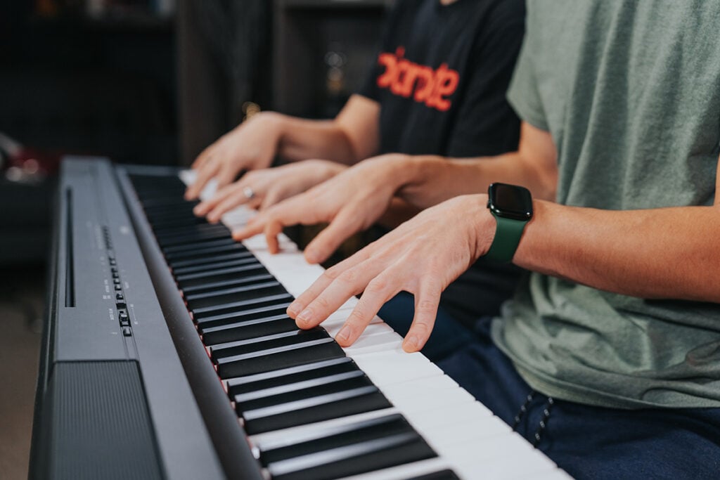 Close-up of two pairs of hands on a keyboard.