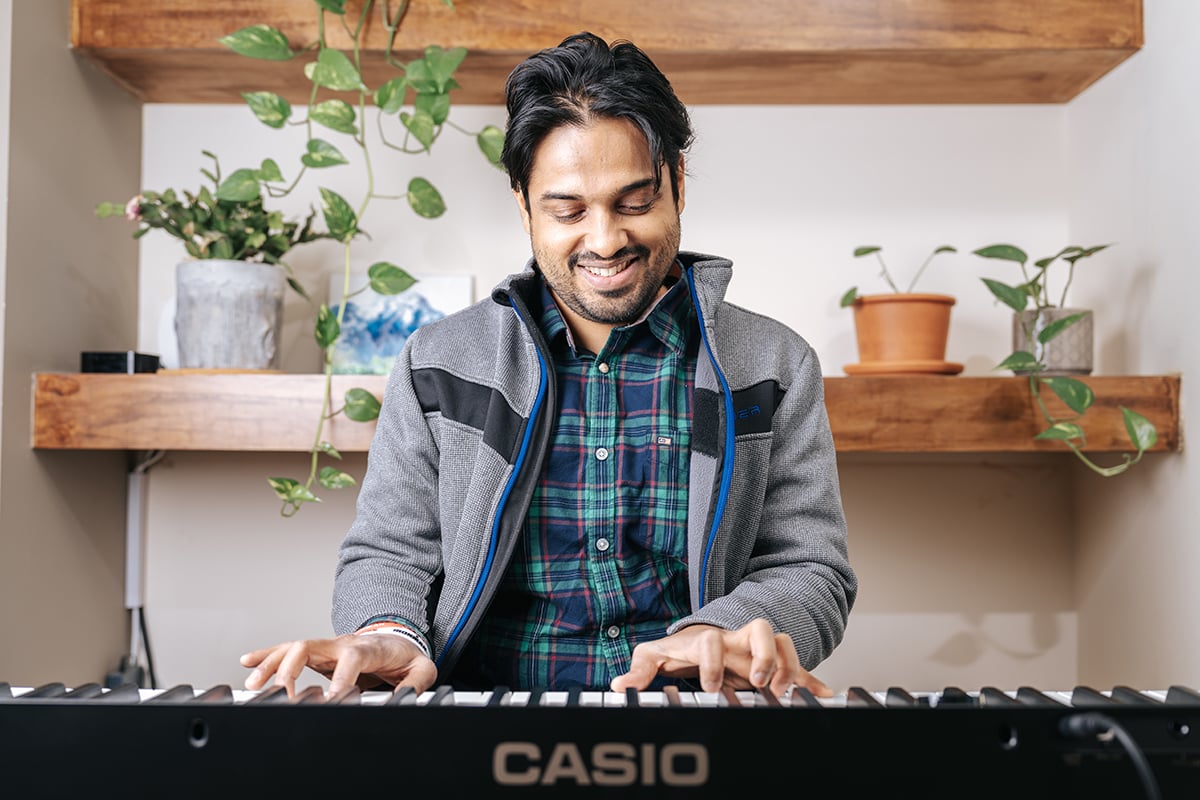 Man in plaid shirt playing piano keyboard