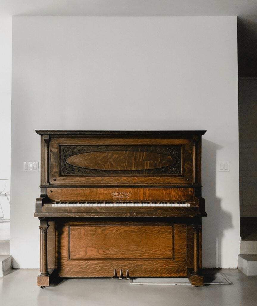 Wooden upright piano in simple room.