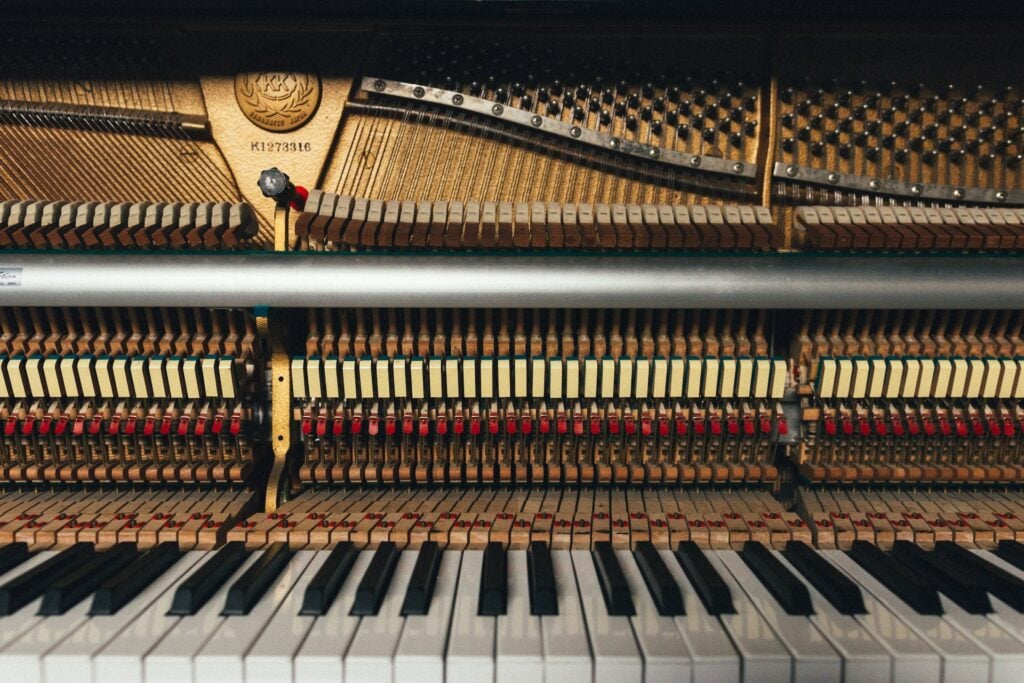 Inside of an upright piano, showing strings and hammers.