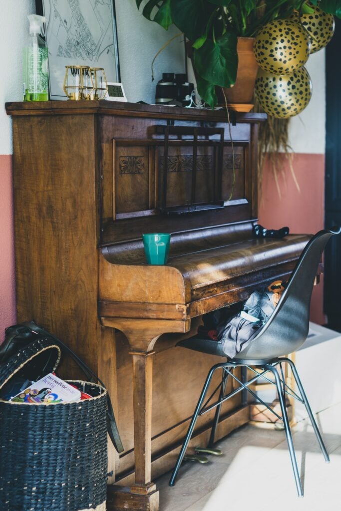 Upright piano with drink on fallboard.