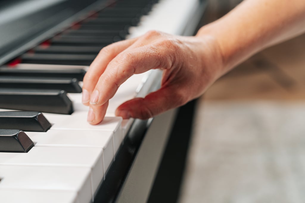 Up close photo of hand performing thumb tuck on piano keyboard.