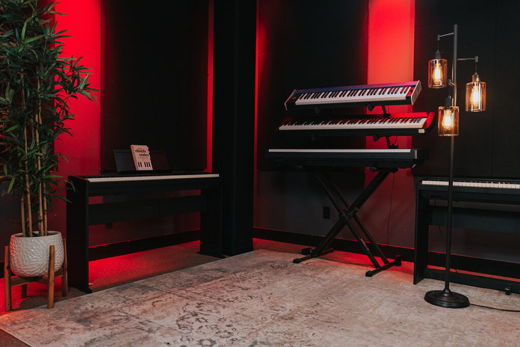 Digital pianos and keyboards in a red lit studio.
