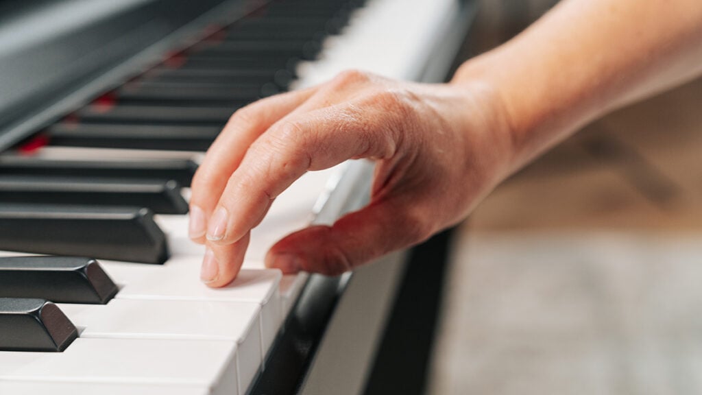 Close up of hand doing thumb tuck on piano keyboard.