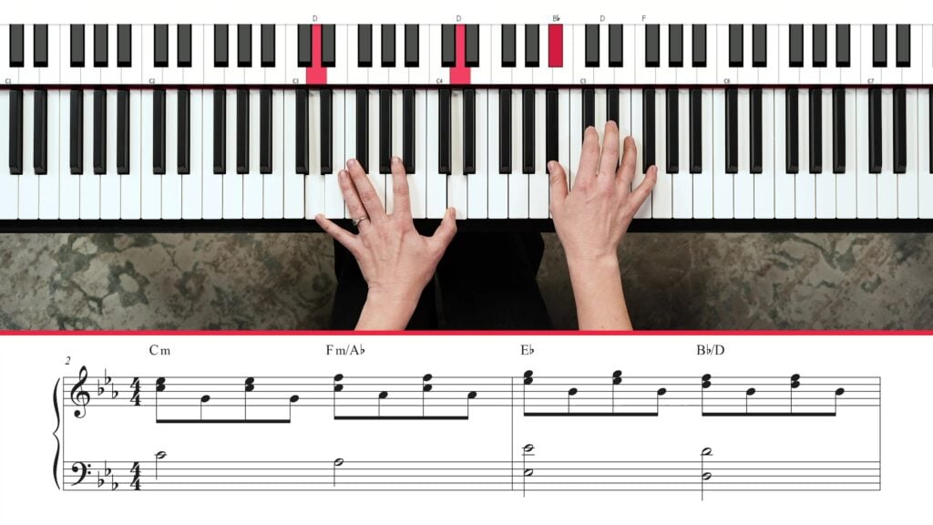 Overhead view of hands playing piano with notation underneath.
