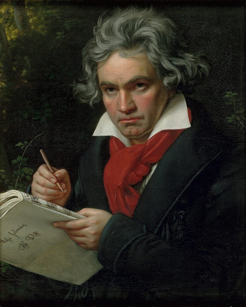 Painting of classical/romantic era man with intense gaze and ruffly grey hair and red scarf holding and writing sheaf of music.