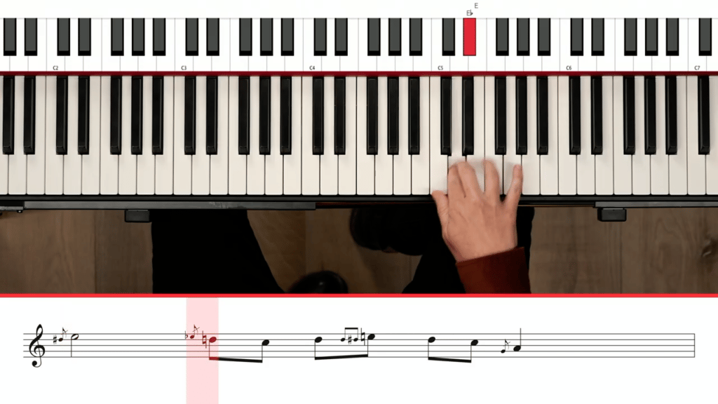 Overview of hands playing piano with standard notation underneath showing grace notes. Piano hacks.