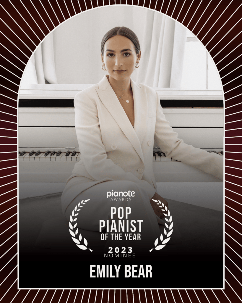 Emily Bear. Young woman in white pantsuit sitting in front of white piano.