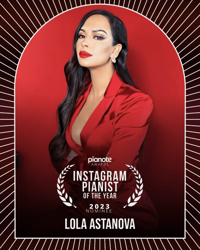 Lola Astanova. Woman with long dark hair in red pantsuit against red background.