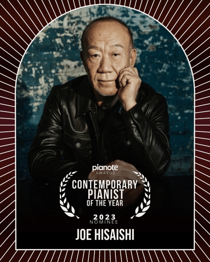 Joe Hisaishi. Older man in black with head in hand in front of marbled blue background.