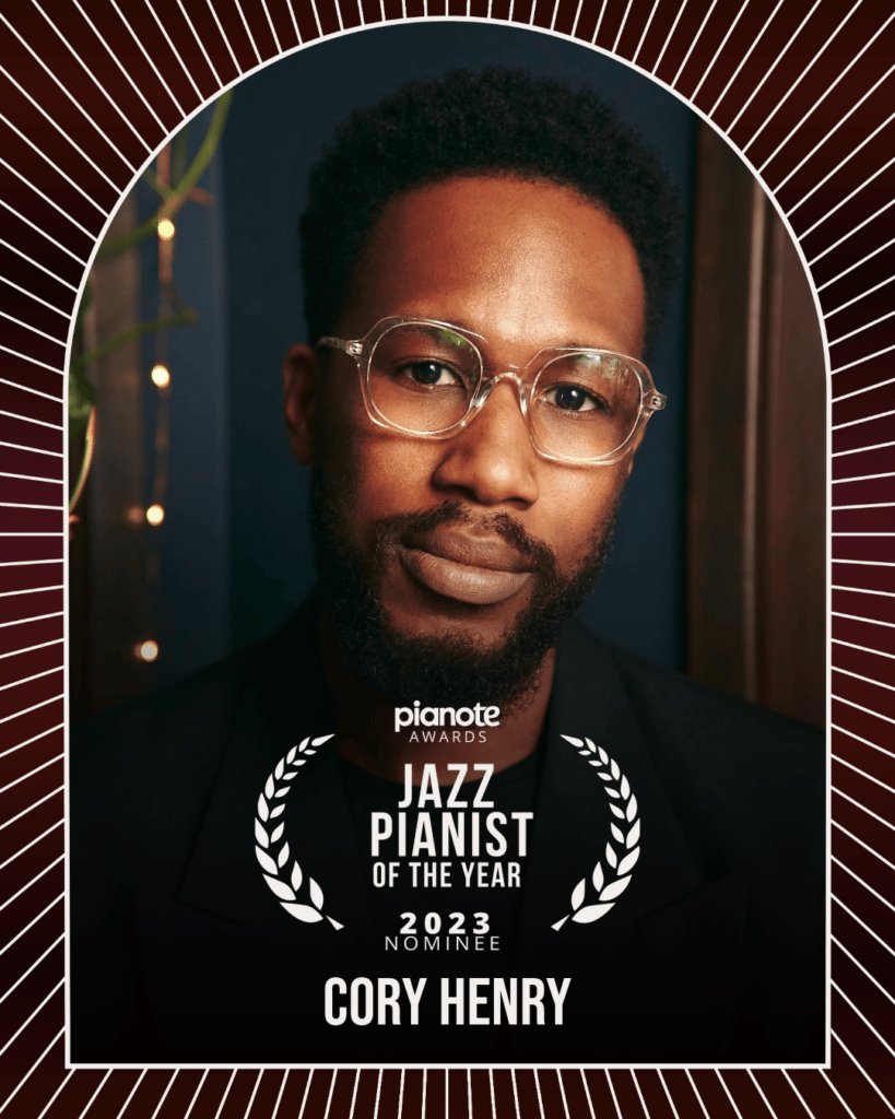 Cory Henry. Portrait of man with glasses and beard.