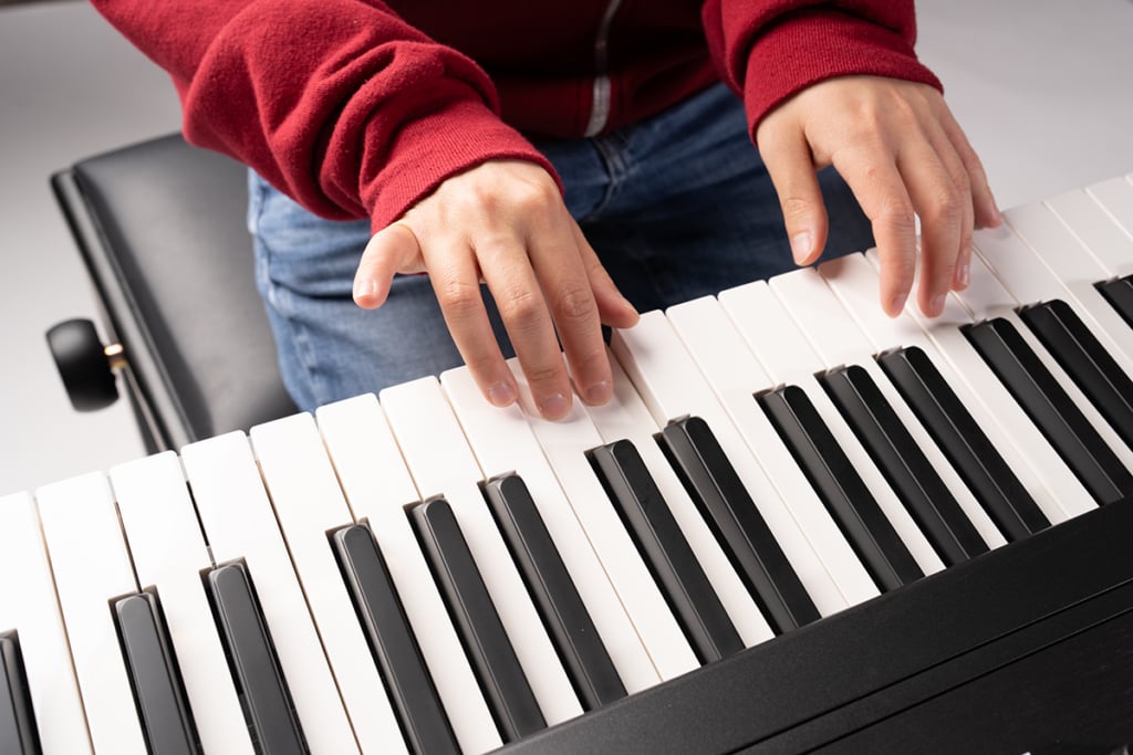 Hands playing piano keyboard.