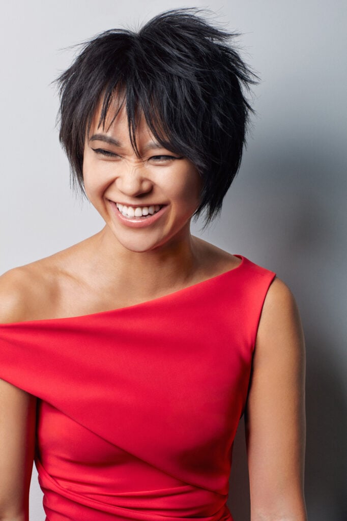 Woman with short black hair in hot pink dress laughing.