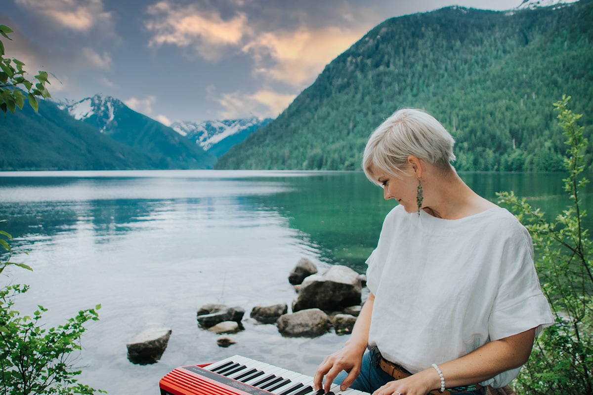 Lisa with keyboard on lap looking behind her at a beautiful lake.