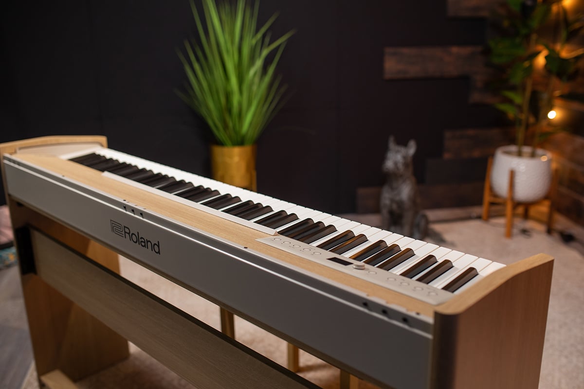 Silver keyboard on wooden stand in homey warm studio setting.
