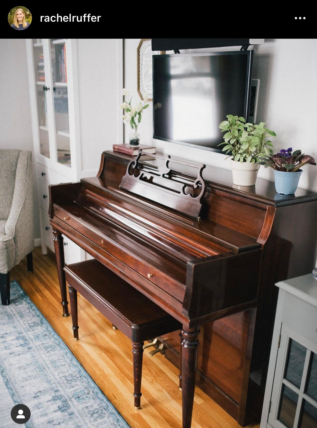 Wooden piano in clean modern room with screens above piano.
