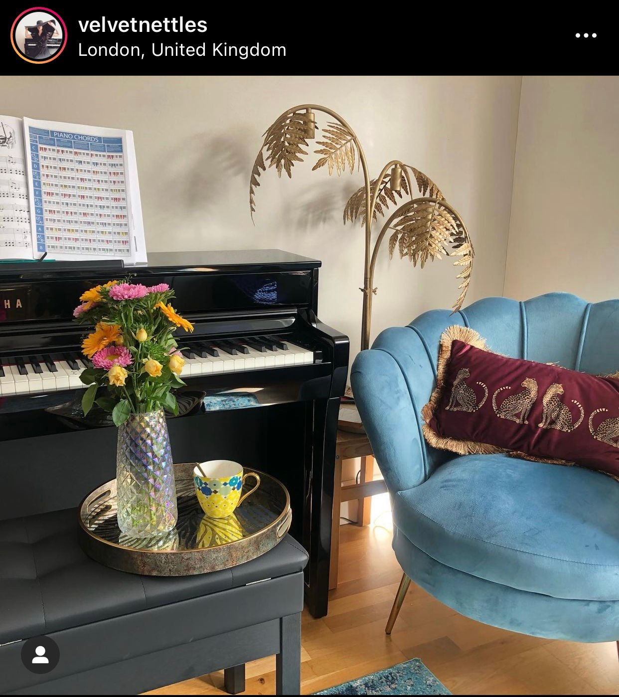 piano with modern armchair, gold plant and tray of tea and bouquet.