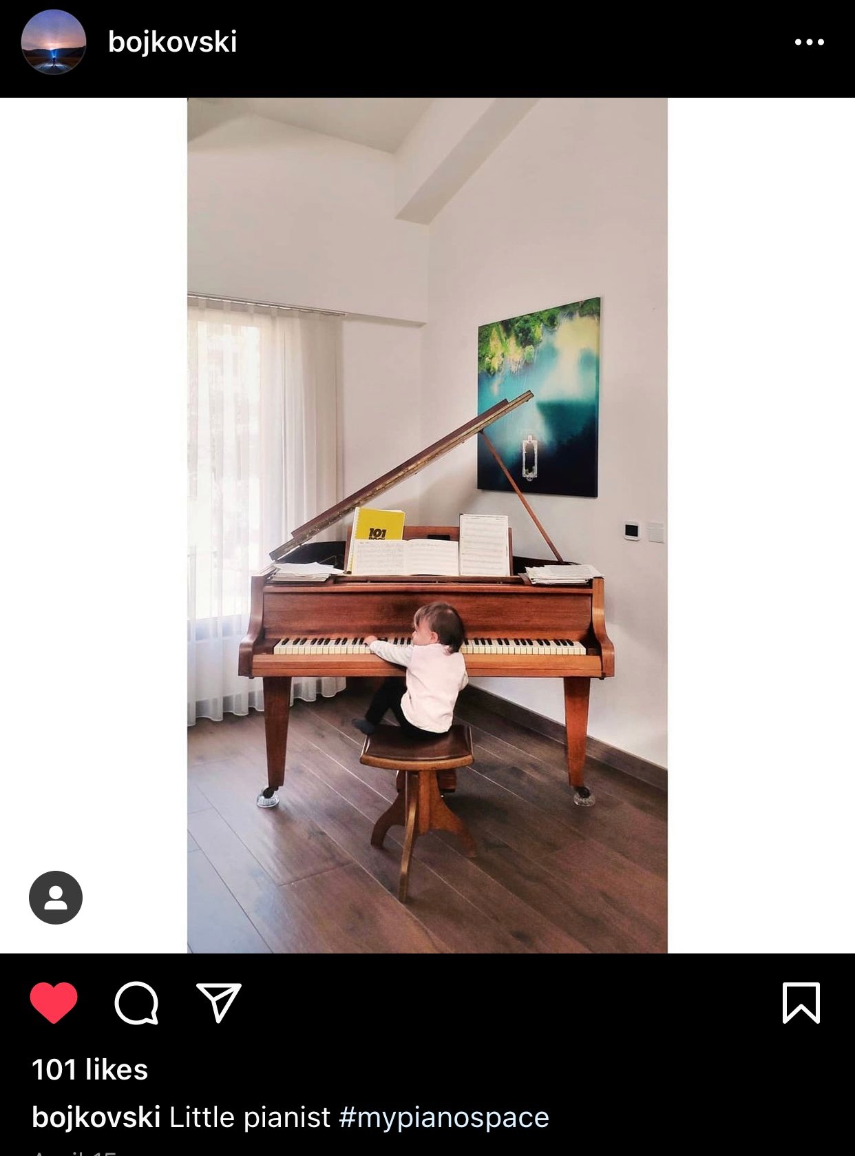 Baby with hand on wooden small grand piano.