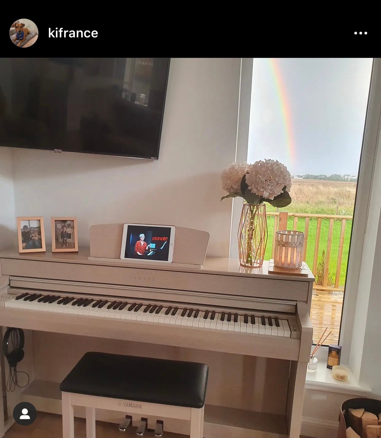White piano with window behind showing rainbow.