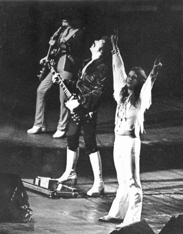 Black Sabbath on stage - black and white photo. Man in white (Ozzy) raising his arms.