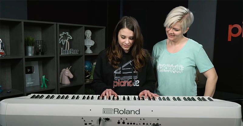 Kaitlyn and Lisa in front of white Roland FP90X.