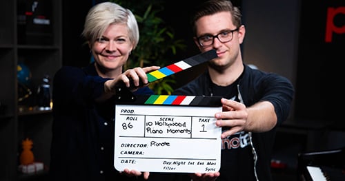 How good is Pianote? Personalized attention through weekly Q&A sessions. Lisa and Sam holding a clapper for a video they're filming.