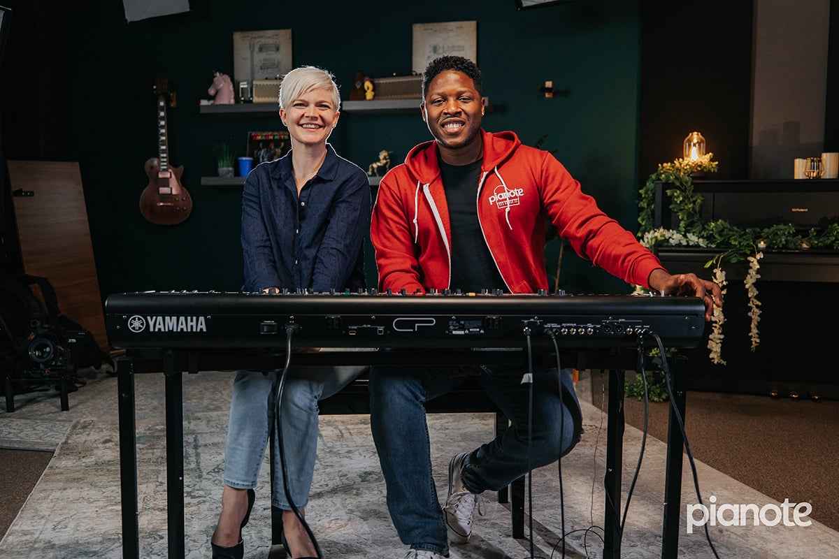 How to play "Lose Yourself" by Eminem on piano. Woman in navy blouse and short platinum hair and man in red hoodie with short dark curly hair sitting behind a digital piano.