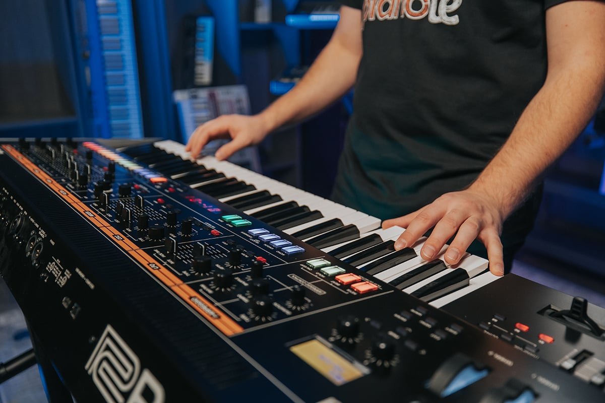 Piano practice motivation. Man's hands playing keyboard synthesizer with many knobs and buttons.