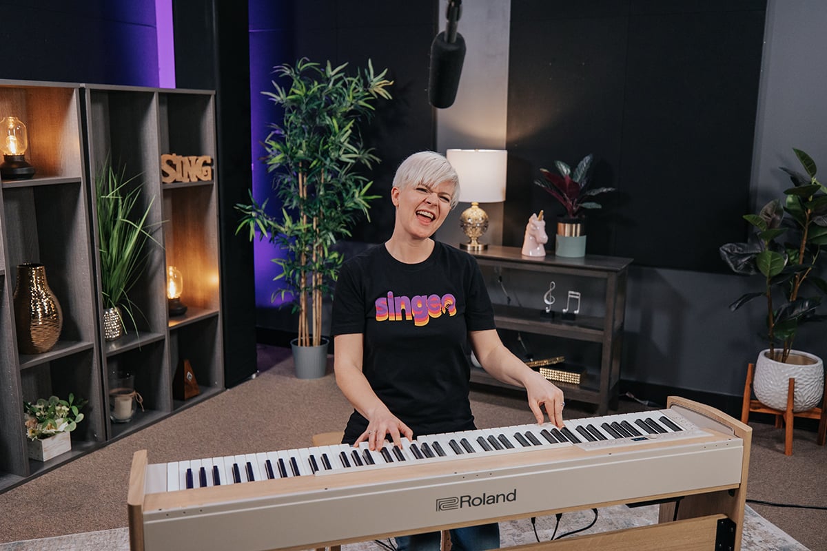 How to sing while playing piano: woman with short platinum hair singing while playing on a keyboard